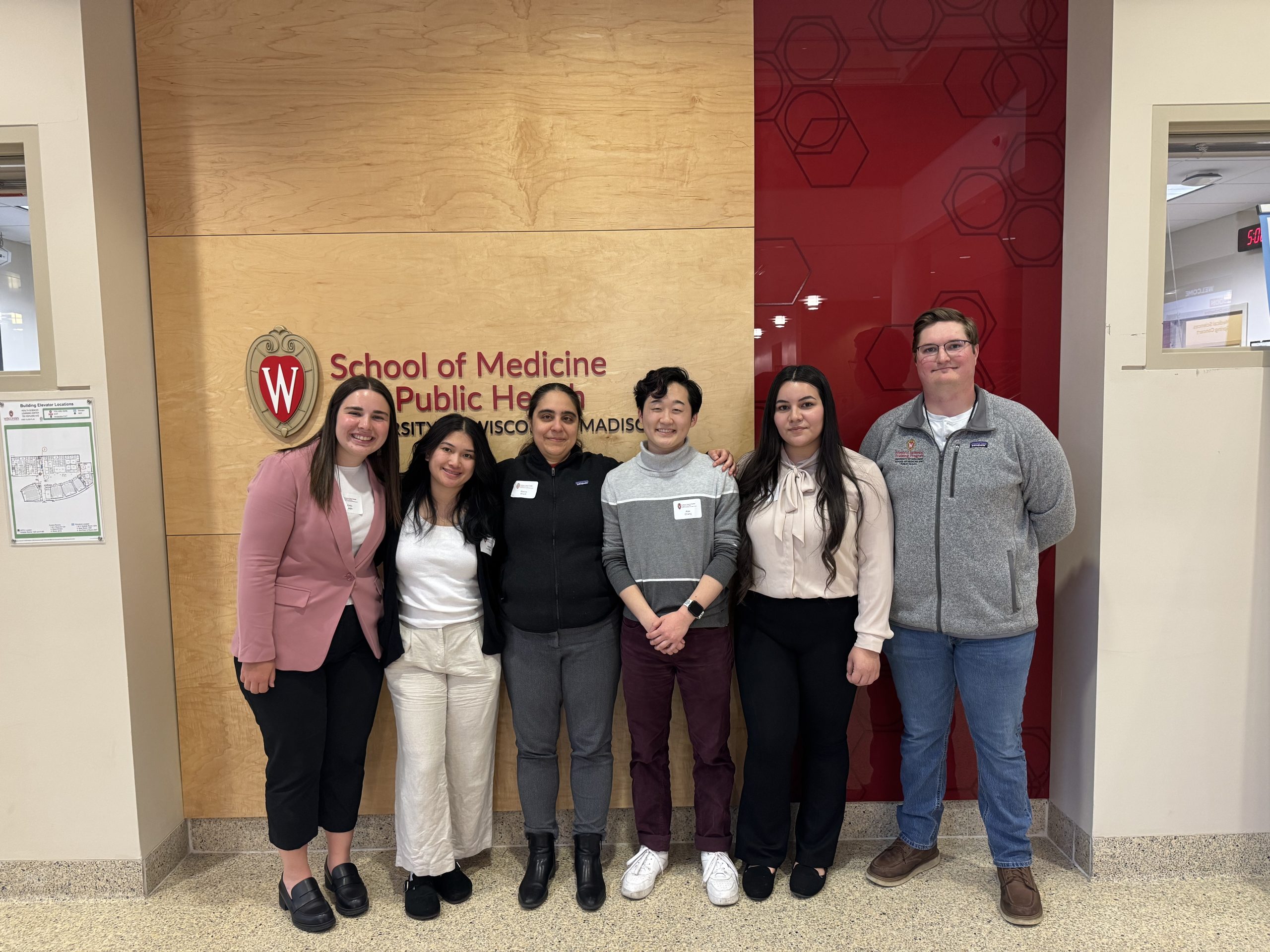 Group photo of Sharifi Lab members in front of a UW SMPH logo